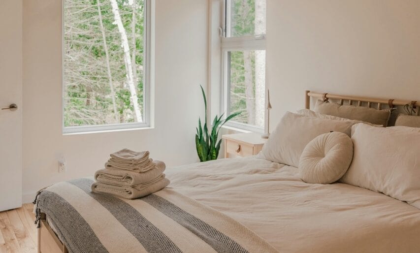 Räätälöity Airbnb-siivous: Huolellisesti siivottu makuuhuone ja pino puhtaita pyyhkeitä sängyn päällä.